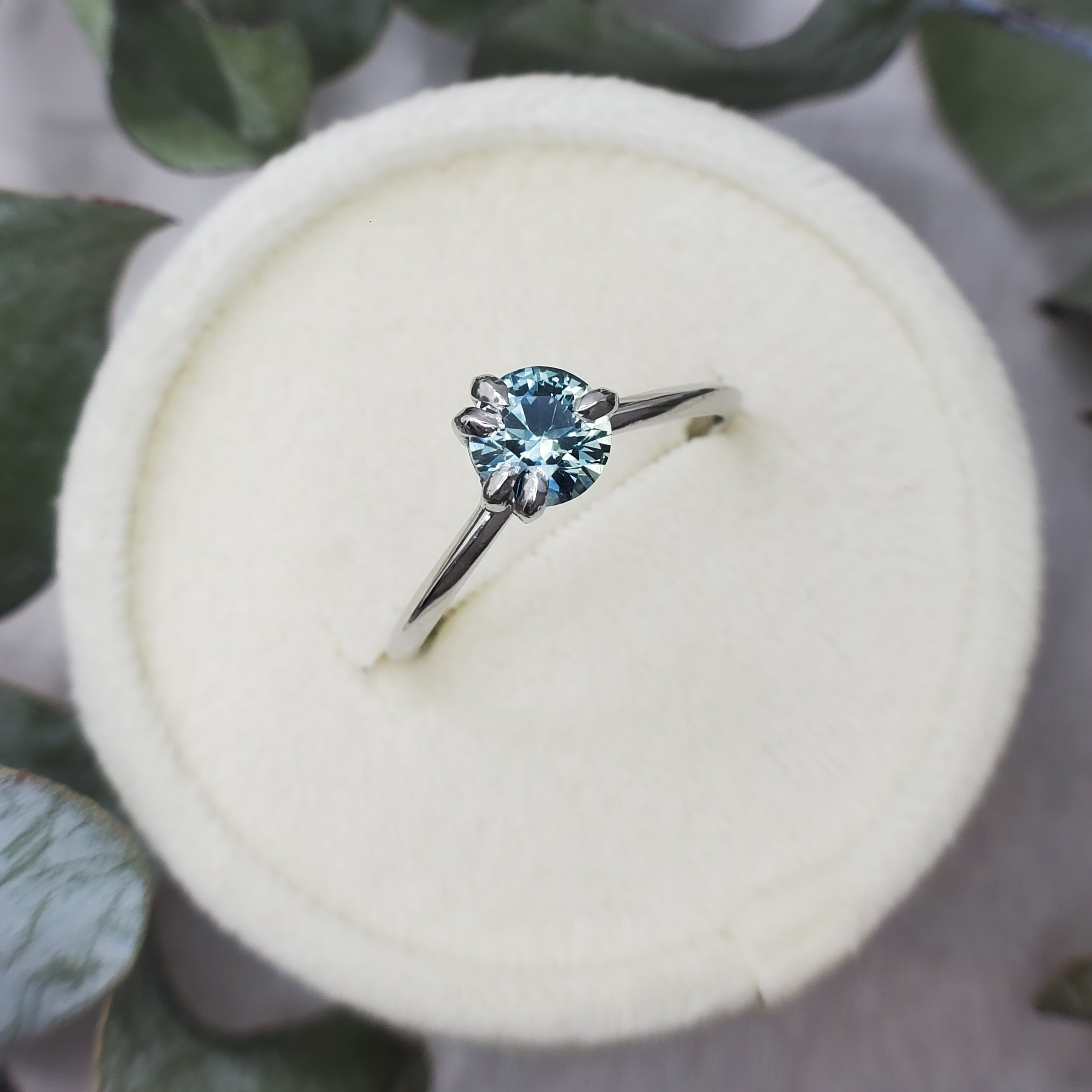 Light Teal Sapphire engagement ring, set with platinum prongs.