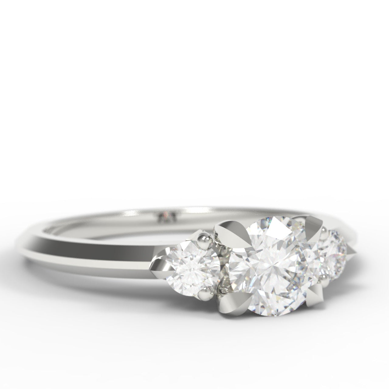 A silver three-stone diamond engagement ring with a brilliant round center stone and two round side stones, set against a clean white background.