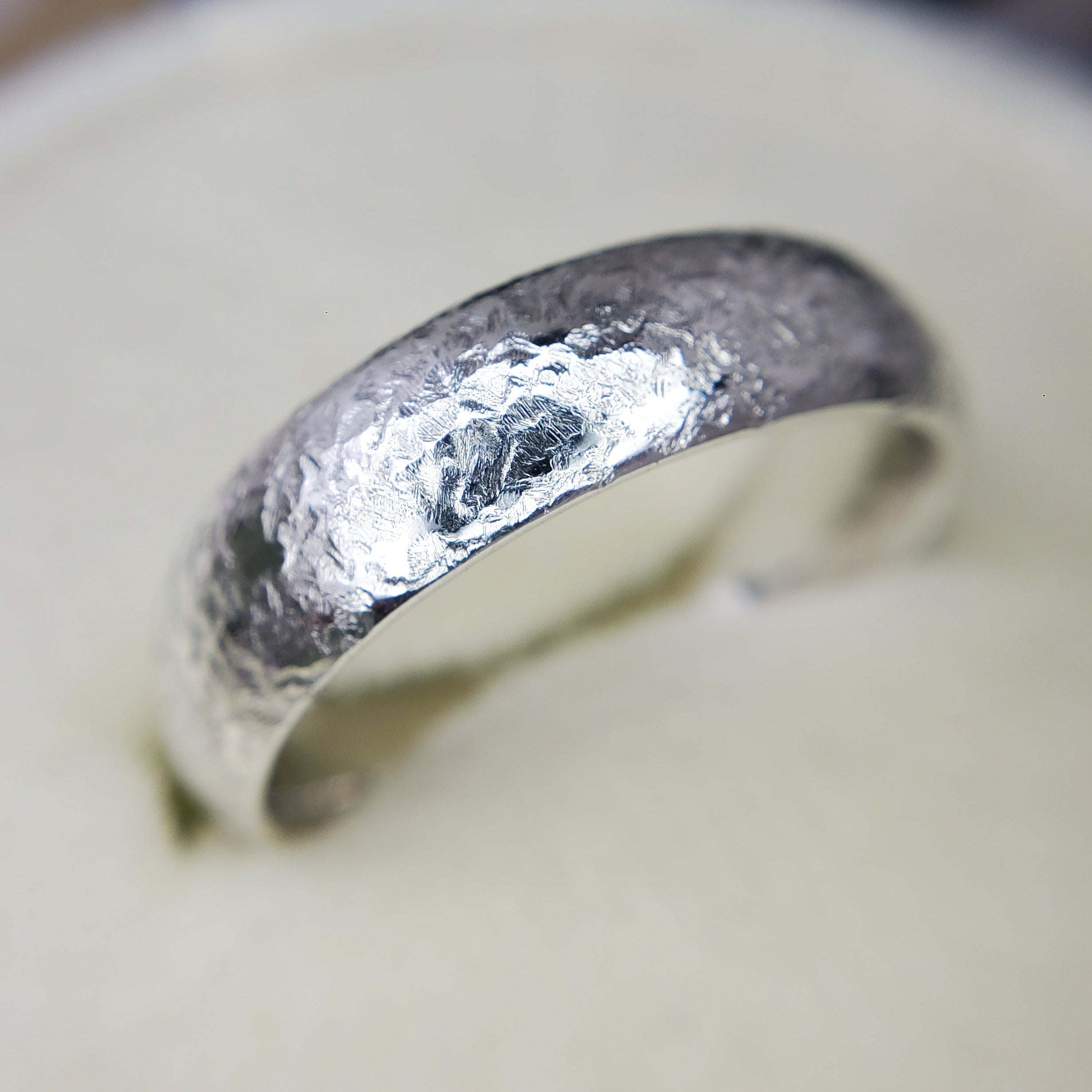 Silver ring with a textured surface on a white background