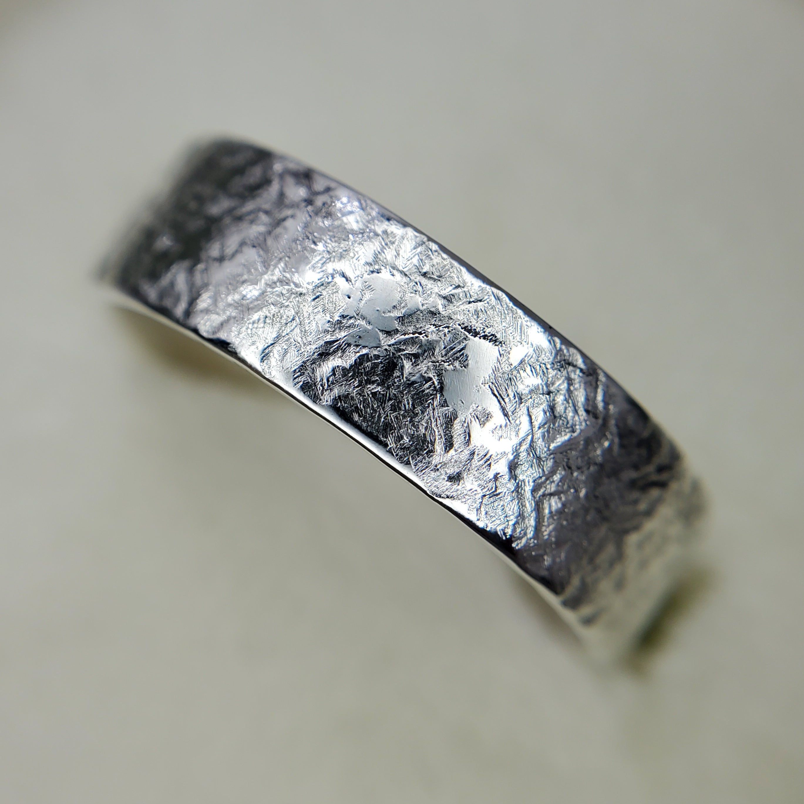 Silver ring with textured surface on a light background